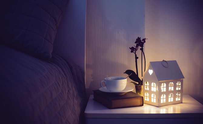 A bed side table with a light and a book