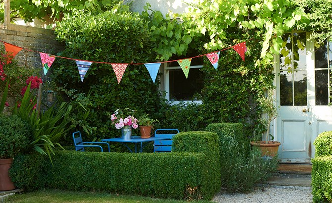 A garden with table and chairs and bunting above
