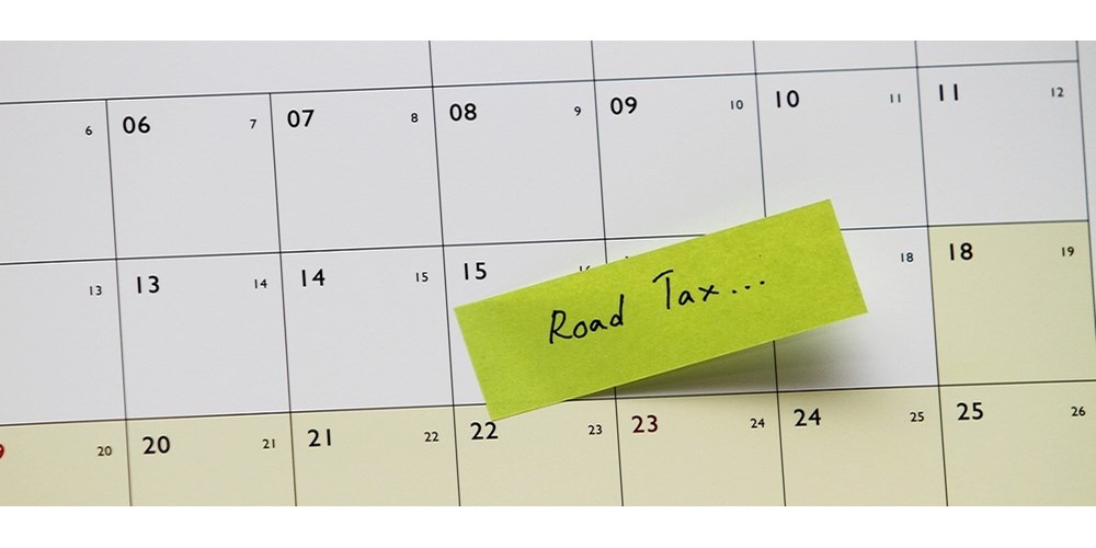 A calendar with a post it note saying "road tax" on one of the dates as a reminder