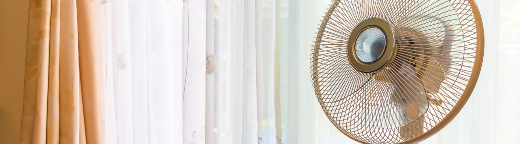 Electric fan in front of curtains